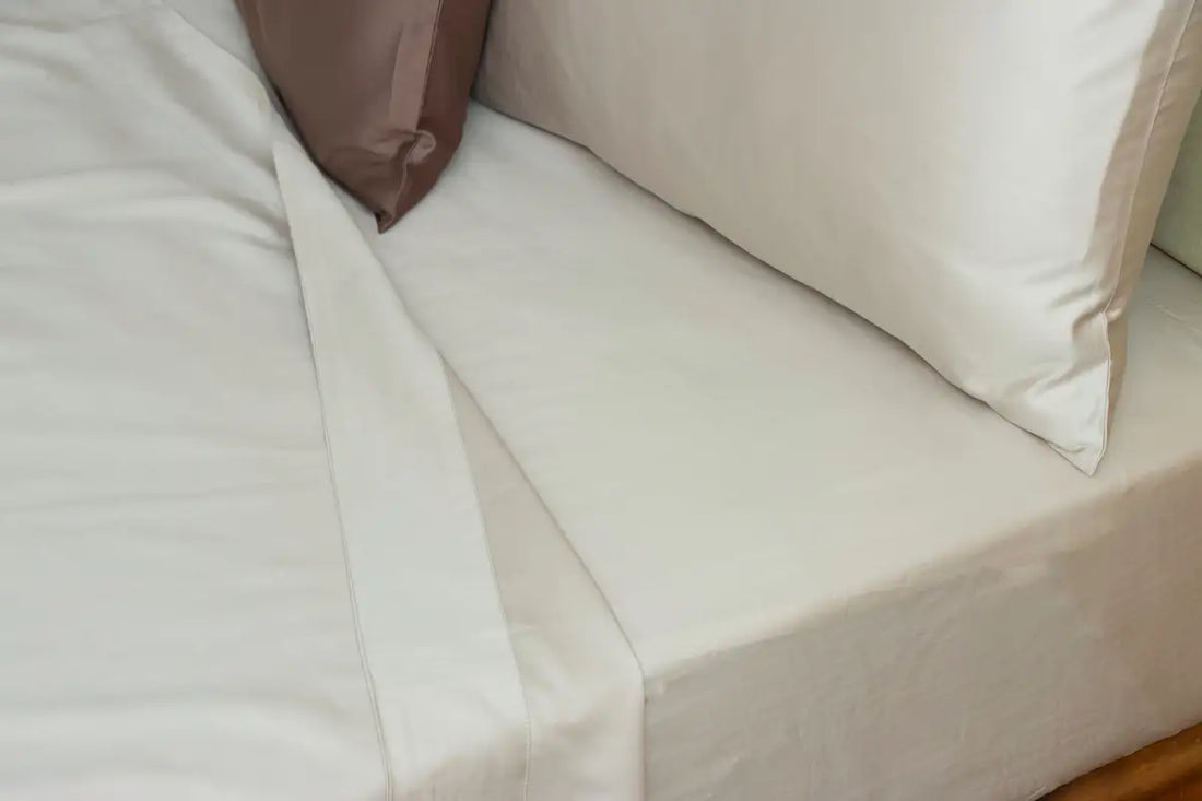 Light grey pure cotton bedsheet neatly made on a bed